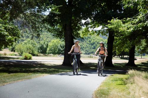 two women in bikini riding bikes down a road at Millbrook Resort in Arrowtown