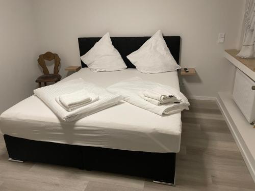 Una cama con mantas blancas y almohadas. en Glessener Braustube, en Bergheim