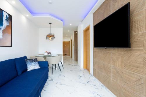 a living room with a blue couch and a television on a wall at Cozy 1st sea line apartment in the quiet area in Los Cristianos
