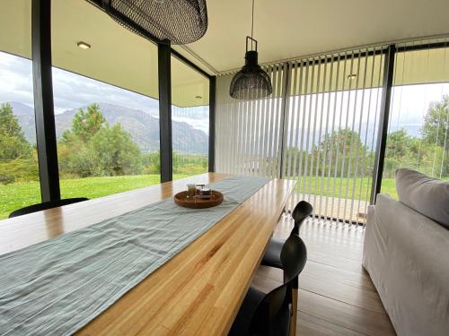 a dining room with a wooden table and large windows at Dpto de Categoría en Arelauquen Golf & Country in San Carlos de Bariloche