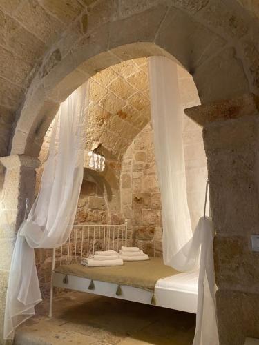 Posto letto in camera in pietra con tende bianche. di Boccaporto a Polignano a Mare