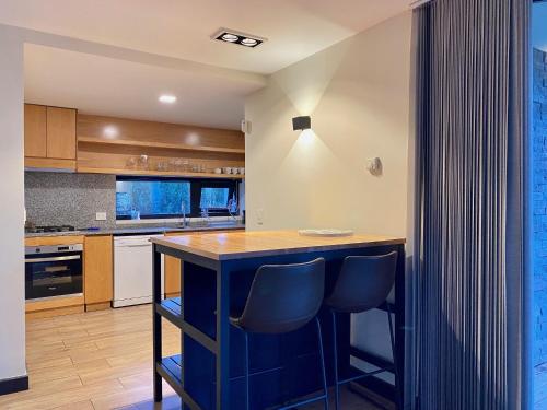 a kitchen with a blue island with two chairs at Dpto de Categoría en Arelauquen Golf & Country in San Carlos de Bariloche