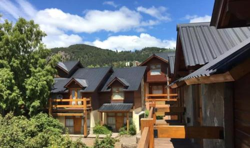una fila de casas de madera con montañas en el fondo en Casa Alta 8 en San Martín de los Andes