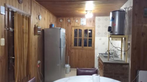 a kitchen with a refrigerator in a room with wooden walls at Cabaña Uspallata, Mendoza. Para 4 personas in Uspallata
