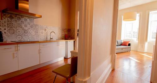 a kitchen with white cabinets and a couch in a room at Casa do Recanto in Porto