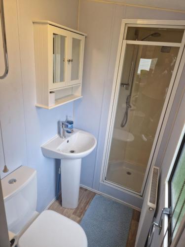y baño con lavabo y ducha. en Lovely caravan at Harts Holiday Park Leysdown-on-Sea en Leysdown-on-Sea