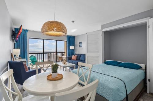 Schlafzimmer mit einem Bett, einem Tisch und Stühlen in der Unterkunft Cottage By the Sea! Renovated Condo with Ocean Views! in Myrtle Beach