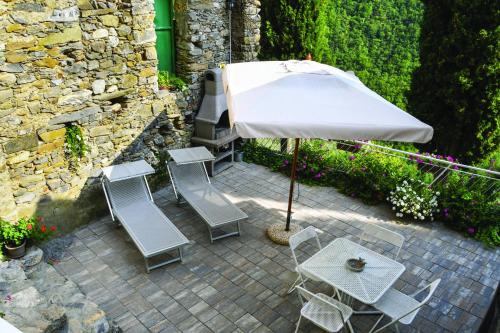 a patio with a table and an umbrella and chairs at Agriturismo Nonnamelia in Nasino