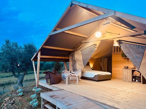 Cette grande tente comprend un lit et une terrasse en bois. dans l'établissement Glamping Grancia, à Grosseto