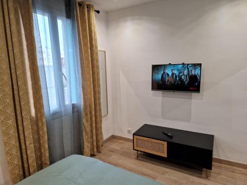 een slaapkamer met een tv aan de muur en een bed bij T2 Cosy proche centre ville avec parking gratuit in Ajaccio