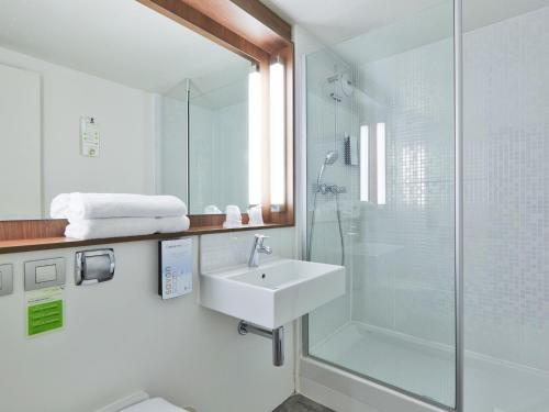 y baño blanco con lavabo y ducha. en Campanile Montesson - Le Vésinet, en Montesson