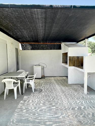 a patio with white chairs and a table and a table and chairs at Casa pet friendly, se reserva con seña in Piriápolis