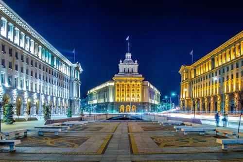 a city street with buildings and a clock tower at night at Cozy 1-Bedroom flat in the very Center of Sofia in Sofia