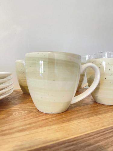 a group of white cups sitting on a wooden shelf at Asteria Apartments in Analipsi