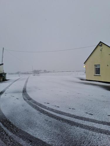 a snow covered road with a building in the middle at Doolin Farm Apartment in Doolin