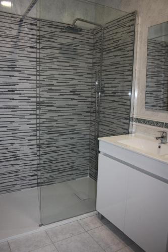 a bathroom with a glass shower and a sink at Arco Da Porta Nova in Braga
