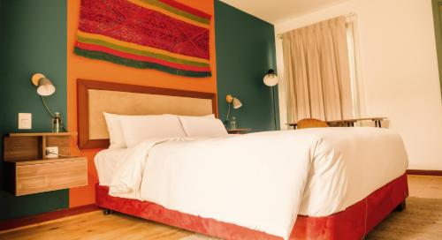 um quarto com uma cama branca e uma parede colorida em Viajero Kokopelli Cusco Hostel em Cusco