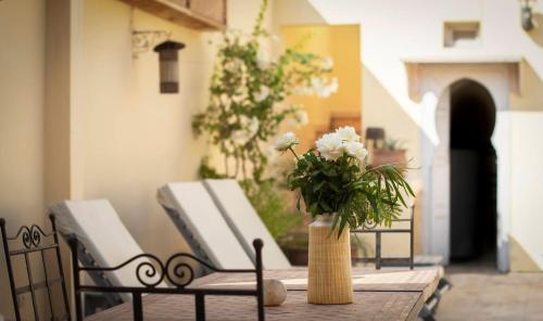 a table with a vase with white flowers on it at RIAD DAR NAOMI in Marrakech