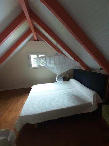 a bedroom with a white bed in a attic at La petite maison dans la prairie in Gros-Morne