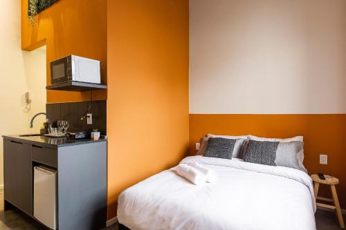 a bedroom with a white bed and a microwave at ZEST Pedroso in Sao Paulo