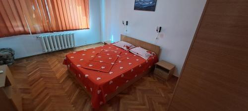 a bedroom with a bed with a red comforter and a window at Apartament DR in Mangalia
