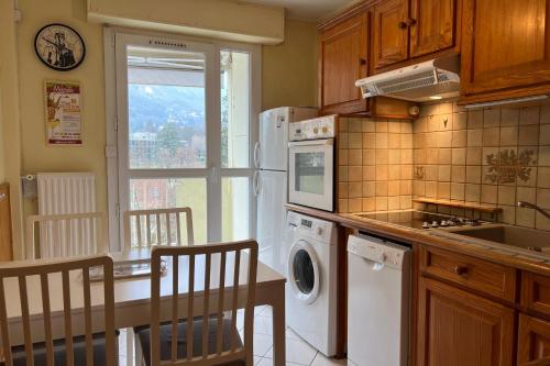 Il comprend une cuisine équipée d'un réfrigérateur et d'une table avec des chaises. dans l'établissement #EV Le Taillat T3 for 4 in Meylan with Terrace, à Meylan