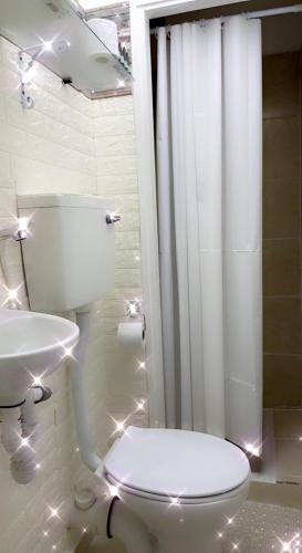 a white bathroom with a toilet and a sink at Shanti Boutique in Netanya