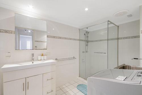 Un baño blanco con lavabo y ducha. en Kirra Beachside, en Gold Coast