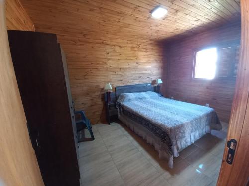 1 dormitorio con 1 cama en una cabaña de madera en Cabaña a estrenar de 2 dormitorios a 3 km de playa, en Santa Vitória do Palmar