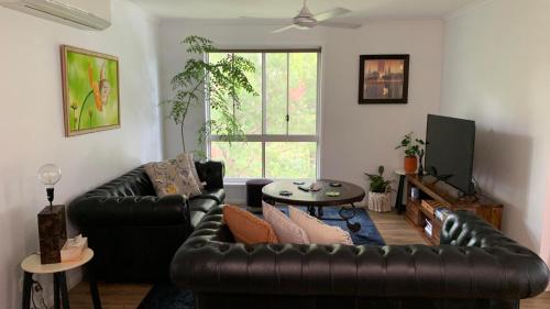 a living room with a leather couch and a table at Bush Beach Retreat in Caloundra