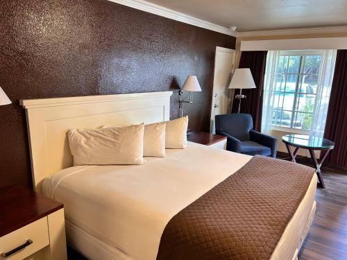 Habitación de hotel con cama y silla en Abby's Anaheimer Inn - Across Disneyland Park, en Anaheim