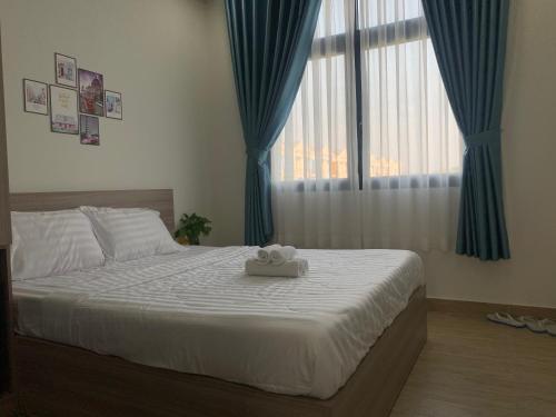una camera da letto con un letto bianco con tende blu e una finestra di Liên’s Mini Hotel a Phu Quoc