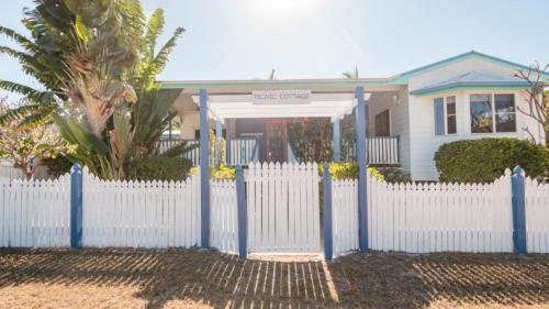 a white picket fence in front of a house at Picnic Cottage, Lovely Home Near The Beach in Picnic Bay