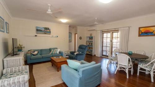 a living room with blue couches and a table at Picnic Cottage, Lovely Home Near The Beach in Picnic Bay