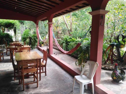 a porch with a table and chairs and a hammock at Hostal Izacalli in Los Potrerillos