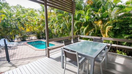 een terras met een tafel en stoelen en een zwembad bij Dolphin Escape Holiday House in Horseshoe Bay