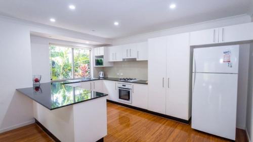 a kitchen with white cabinets and a white refrigerator at Dolphin Escape Holiday House in Horseshoe Bay