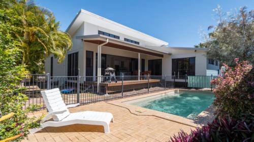a dog sitting next to a house with a swimming pool at Barefoot Beach House in Horseshoe Bay