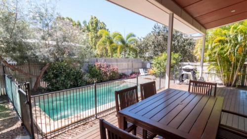 a deck with a table and chairs and a swimming pool at Barefoot Beach House in Horseshoe Bay