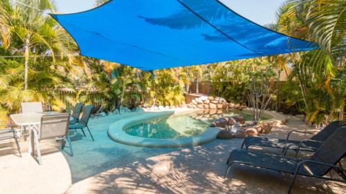 a pool with a blue umbrella next to a table and chairs at The Ponderosa Holiday House in Horseshoe Bay