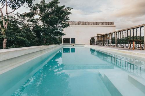 a swimming pool with blue water in front of a building at Yum Kaax Boutique Villa in Tulum