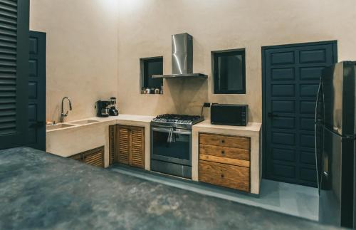 a kitchen with a stove and a sink and a refrigerator at Yum Kaax Boutique Villa in Tulum