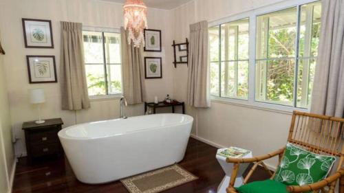 a bathroom with a large white tub and a chair at The Butterfly House, Beautiful Home Near The Beach in Horseshoe Bay