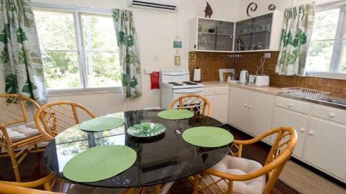 The Butterfly House, Beautiful Home Near The Beach في Horseshoe Bay: مطبخ مع طاولة سوداء وكراسي خشبية