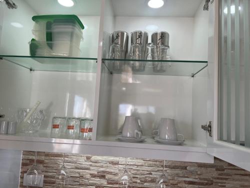 a kitchen with glass shelves with cups and utensils at Sea sand sun resort Deluxe Mae Rumphueng beach in Ban Chak Phai