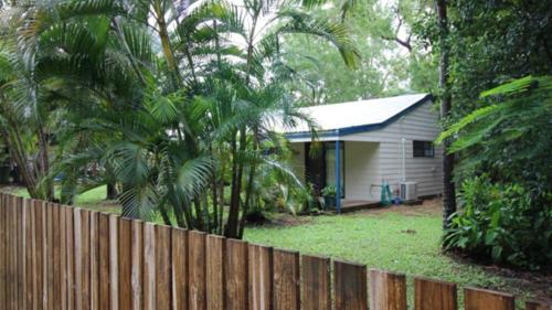 a fence in front of a house with palm trees at Seaward Cottage, Nelly Bay in Nelly Bay