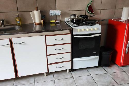 Il comprend une cuisine équipée d'une cuisinière et d'un réfrigérateur rouge. dans l'établissement Departamento Ushuaia, à Ushuaia