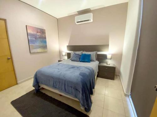 a bedroom with a bed with a blue comforter at Moderno condo de 1 rec con alberca 5 mins a playa 103b in Cabo San Lucas