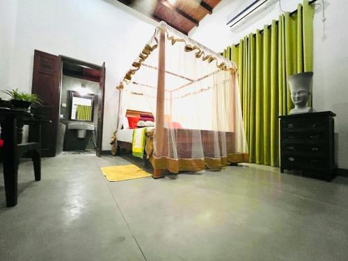 a bedroom with a bed and green curtains at Krishan Villa in Negombo