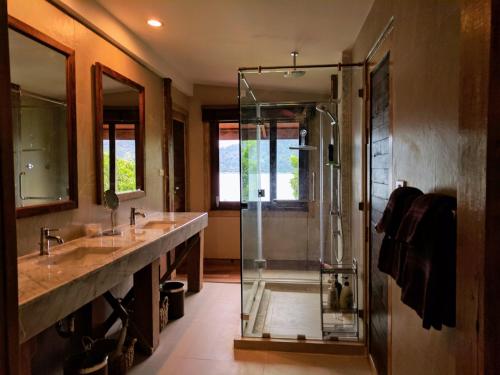 uma casa de banho com 2 lavatórios e uma cabina de duche em vidro. em Cashewnut Cove em Koh Lipe
